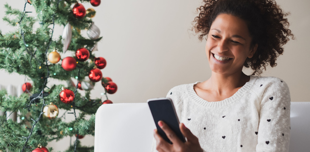 Woman near Christmas tree holds phone